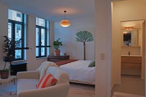 een slaapkamer met een bed, een bank en ramen bij l'ostendaise in Oostende