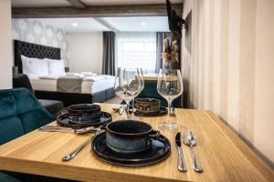 a wooden table with glasses and plates on top of it at Hotel Demanova Apartments Dependance in Liptovský Mikuláš