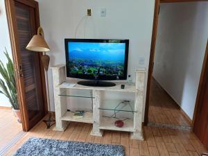 a television sitting on a stand in a room at Casa Lot Fechado, Churrasqueira, Piscina, Toboágua, parque para crianças , Internet in Piracaia