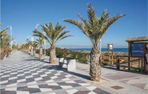 einen Gehweg mit Palmen, einer Bank und dem Meer in der Unterkunft Stunning Home In Gran Alacant With Outdoor Swimming Pool in Santa Pola