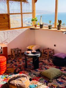 a living room with a table and a window at Azoul Surf Hostel Taghazout in Taghazout