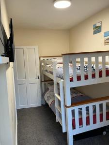 a bedroom with two bunk beds and a flat screen tv at Seagull Cottage in Looe