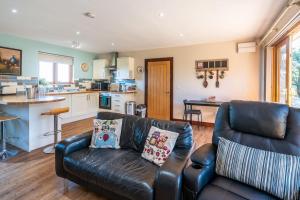 a living room with a leather couch and a kitchen at Milestone House in Somersham