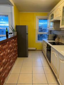 een keuken met gele muren en een zwarte koelkast bij Comfy, cosy, and spacious apartment near Paris in Bezons