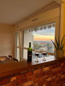 twee glazen wijn zittend op een bar met een raam bij Comfy, cosy, and spacious apartment near Paris in Bezons