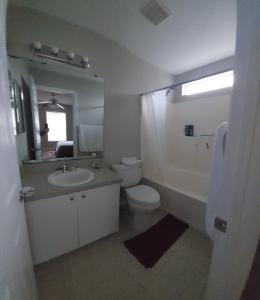 a bathroom with a sink and a toilet and a mirror at Close to beach in Fort Pierce