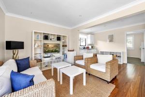 a living room with white furniture and blue pillows at Breakers on Orion Beach Vincentia in Vincentia