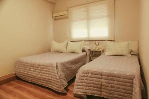 2 camas en una habitación pequeña con ventana en Alas Hotel en San Rafael