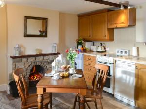 a kitchen with a table with a fireplace in it at Buckswell Cottage in Hury