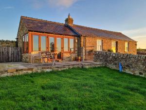 uma casa de pedra com uma mesa e uma cerca em Buckswell Cottage em Hury