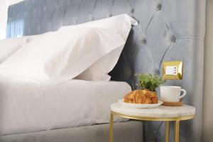 a table with a plate of croissants and a cup of coffee at Toscano Palace Luxury Rooms Catania in Catania