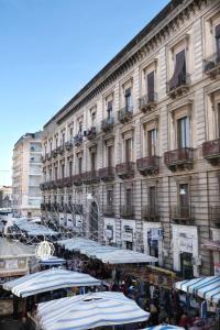 een groot gebouw met tafels en parasols ervoor bij Toscano Palace Luxury Rooms Catania in Catania