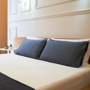 a bed with two blue pillows on it at Toscano Palace Luxury Rooms Catania in Catania