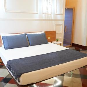 a bedroom with a large bed with blue pillows at Toscano Palace Luxury Rooms Catania in Catania