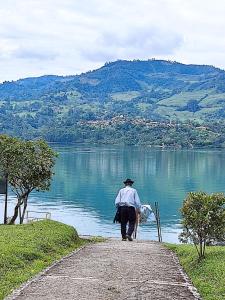 un hombre caminando por un camino junto a un lago en Glamping Tiny house 