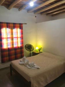 1 dormitorio con cama, lámpara y ventana en Chalet de montaña cerca de Nono en Las Rabonas