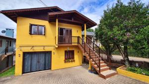 ein gelbes Haus mit einer Treppe davor in der Unterkunft Casa Palace Canela in Canela