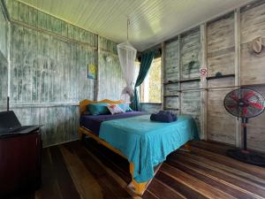 1 dormitorio con 1 cama en una habitación con paredes de madera en Old Bocasso, en Bocas Town