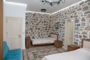 Cette chambre comprend 2 lits et un mur en pierre. dans l'établissement Luxury Villa Saint Nikolas, à Voskopojë