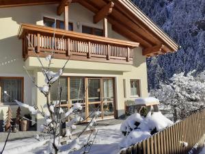 une maison avec un balcon dans la neige dans l'établissement Apart Larcher, à Kaunertal