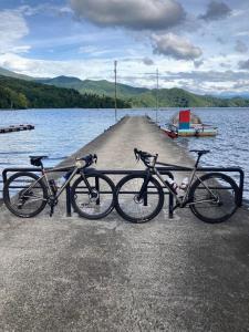 due biciclette parcheggiate su un molo vicino a un corpo d'acqua di Astuto Riders House ad Annaka