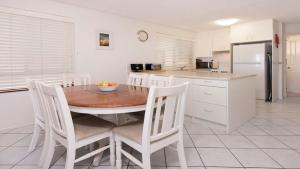 a kitchen with a wooden table and white chairs at Kookaburra Court Unit 1 Bulcock Beach QLD in Caloundra
