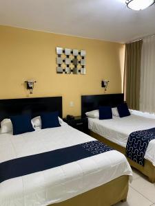 1 dormitorio con 2 camas y almohadas azules y blancas en HOTEL IMPALA DE TAMPICO en Tampico