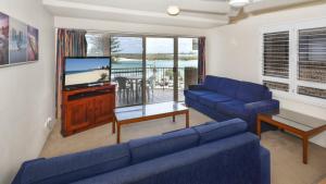 een woonkamer met een blauwe bank en een tv bij Kookaburra Court Unit 3 Bulcock Beach QLD in Caloundra