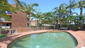 een groot zwembad met palmbomen en een gebouw bij Kookaburra Court Unit 3 Bulcock Beach QLD in Caloundra