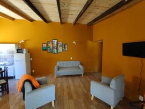 a living room with two chairs and a flat screen tv at Villas Laura in Punta Del Diablo