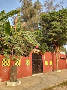 un edificio rojo con una puerta negra y árboles en Auberge Africa Thiossane, en Saly Portudal
