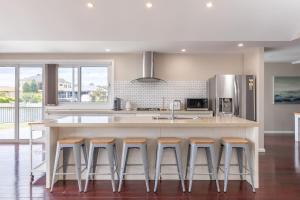 a kitchen with a large island with four bar stools at King George Parade in Forster