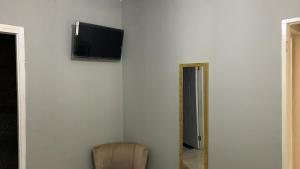 N & A PALACE في خليج مونتيغو: غرفة بها كرسي وتلفزيون على جدار