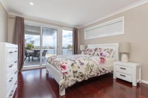 a bedroom with a bed and a balcony with a table at King George Parade in Forster