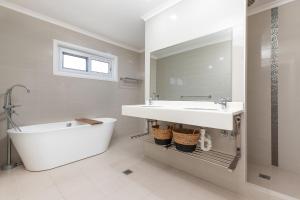 a white bathroom with a tub and a sink at King George Parade in Forster +15 photos