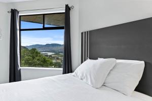 1 dormitorio con cama blanca y ventana grande en The Vista Inn en Kamloops