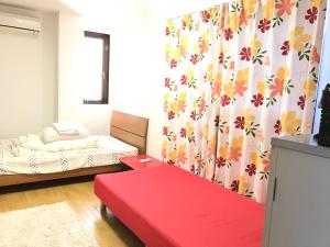 a small room with a red bench and a bed at IM guest house in Osaka