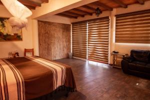 um quarto com uma cama, uma cadeira e uma janela em Hotel boutique Teocalli em Tepoztlán