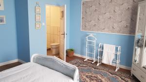 een blauwe kamer met een bed en een badkamer bij Les Cygnes Noirs in Aujac
