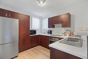 a kitchen with wooden cabinets and a white appliance at Coastal Cove Huskisson in Huskisson