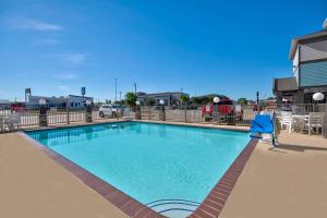 una gran piscina con una silla azul y una casa en Studio 6-Port Arthur, TX - SE, en Port Arthur