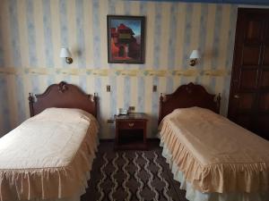 a hotel room with two beds and a picture on the wall at Hostal Paola in Sucre