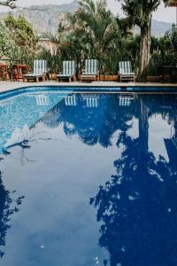 a swimming pool with chairs and trees and mountains at Hotel boutique Teocalli in Tepoztlán