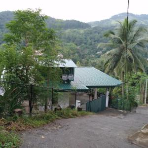 una casa con techo verde y valla en Jayathmaguest en Peradeniya