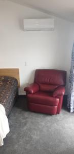 una sedia in pelle rossa in una stanza con un letto di Richmond Motel and Holiday Park a Richmond