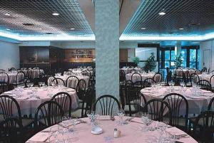 a dining room with tables and chairs with white tablecloths at Hotel Aurora in Chiavenna