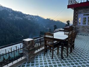 a table and chairs on a balcony with a view at Calm Paradise in Shimla
