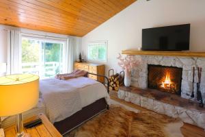 a bedroom with a fireplace and a bed and a television at Picturesque Cabin 2 Balconies, Walk to Lake! in Crestline