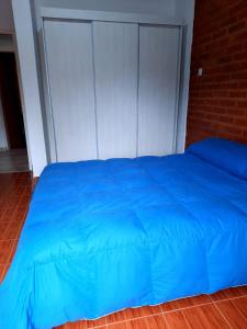 a blue bed in a room with a brick wall at Nuova Costa Cabañas in Los Molles