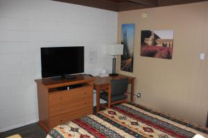Dormitorio con cama y tocador con TV en Flamingo Motel en Penticton